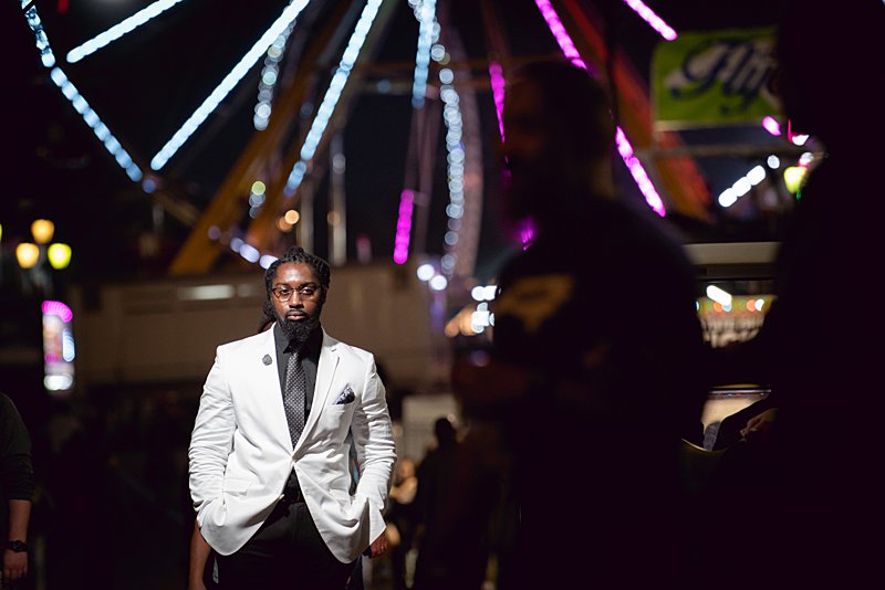 Black man with locs in white blazer at nc state fair engagement session