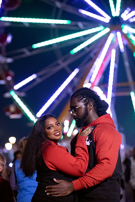Couple standing in front of ferris wheel at nc state fair