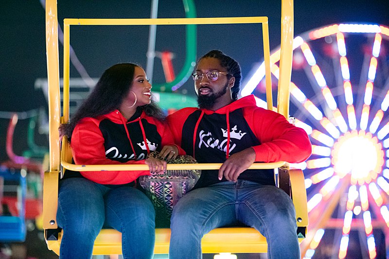 Black couple in king and queen hoodie on ride at fair