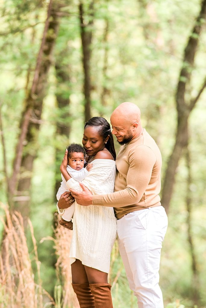 Black family outdoors with newborn wearing neutral colors