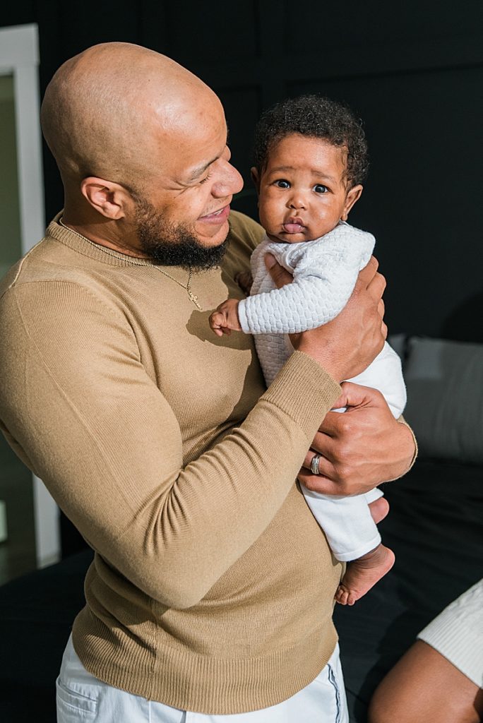 Black father in bedroom with newborn son