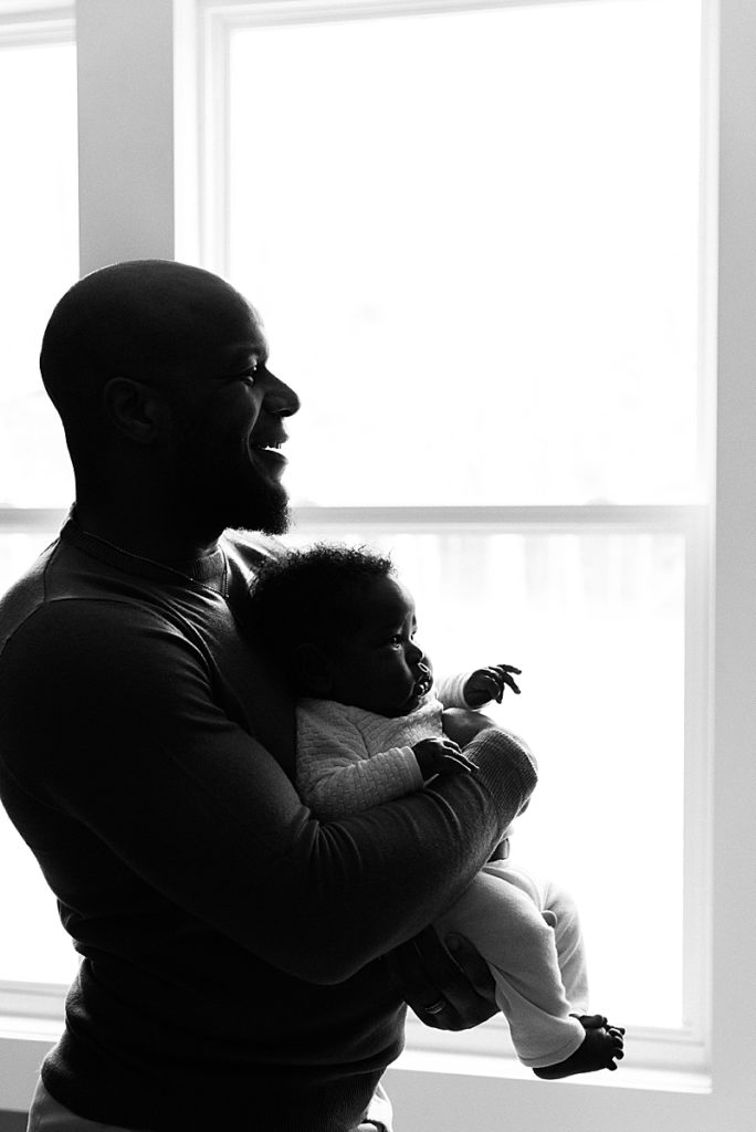 Silhouette of Black father in bedroom with newborn son