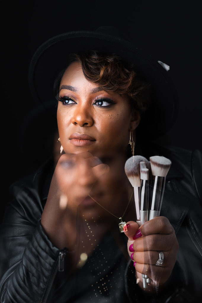 Double Exposure Unique headshot Photograph of Black NC makeup artist holding her brushes against black backdrop Wonderfully Made By Tay NC