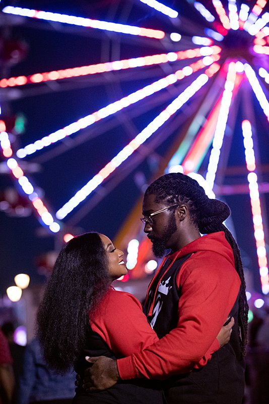 Couple standing in front of ferris wheel at nc state fair